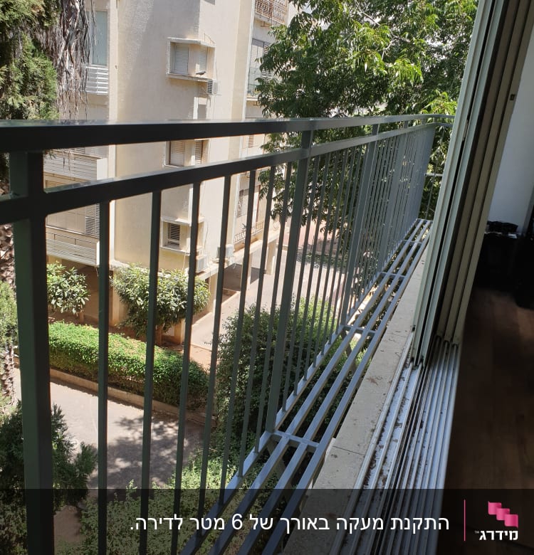 מעקה מתכת במרפסת עם נוף לעצים ובניין סמוך